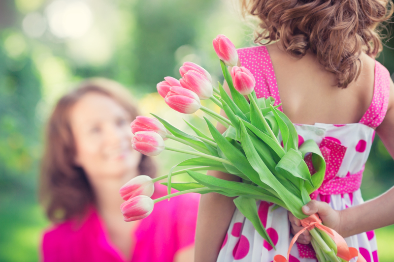 Florist preparing foam-free flower arrangement using chicken wire and glass vase on workbench